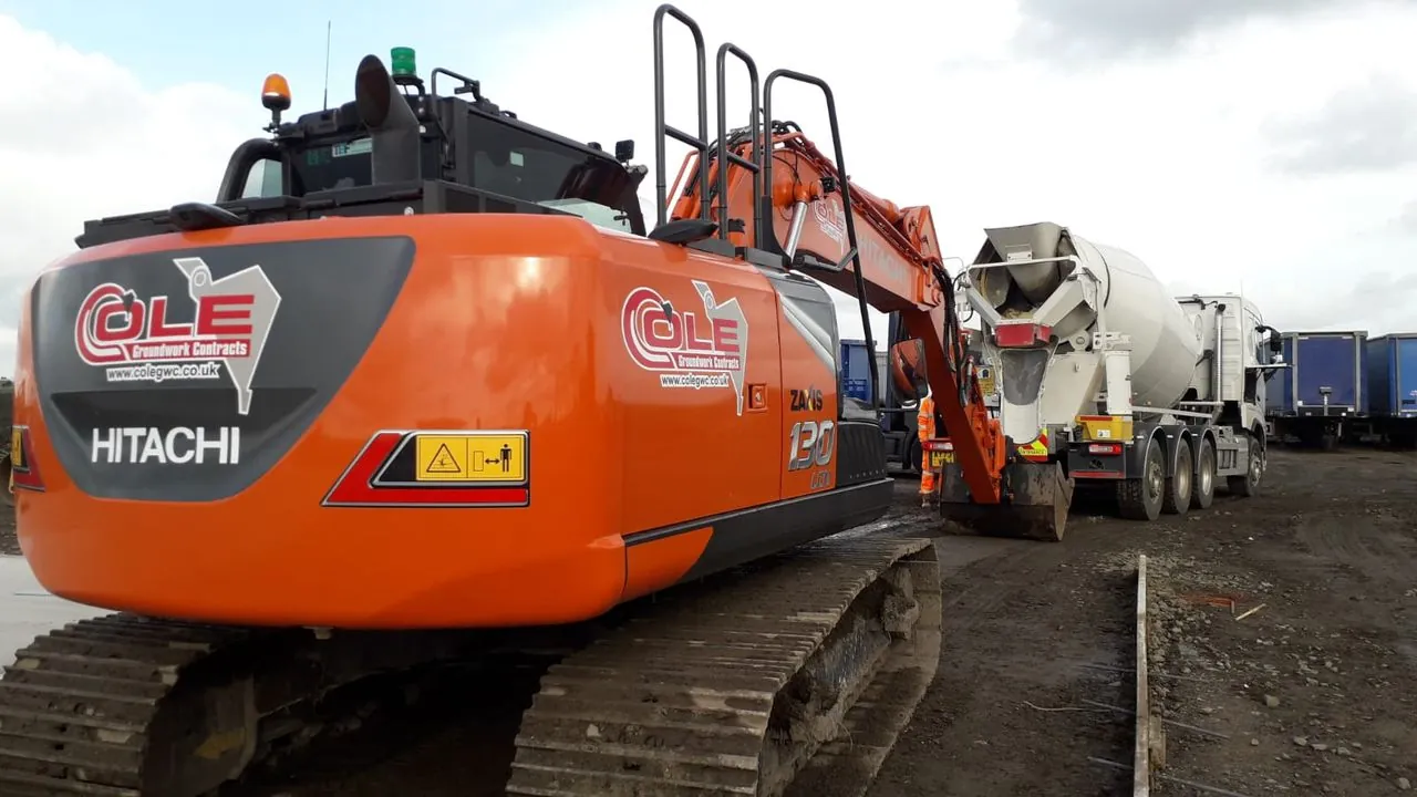 A Cole-branded Hitachi excavator beside a concrete mixer on site